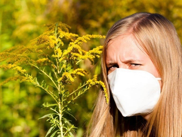 Girl with mask standing by goldenrod