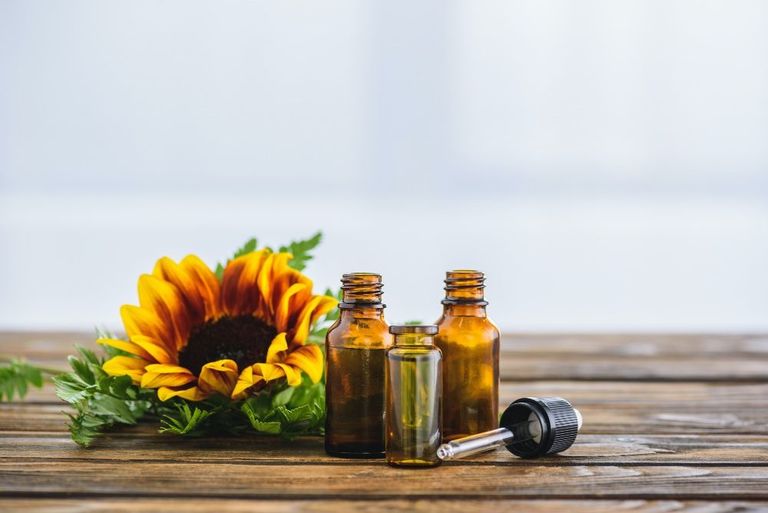 Amber glass dropper bottles on a wooden table with a sunflower