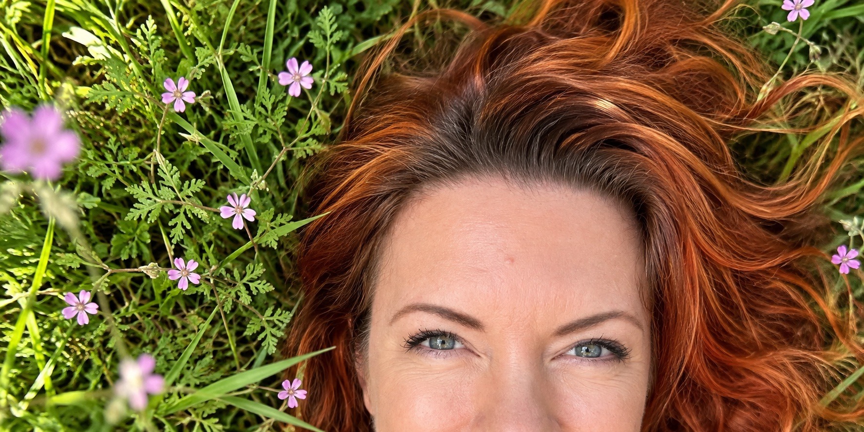 Seneca lying in the grass among small pink Filaree flowers, looking up at the sky